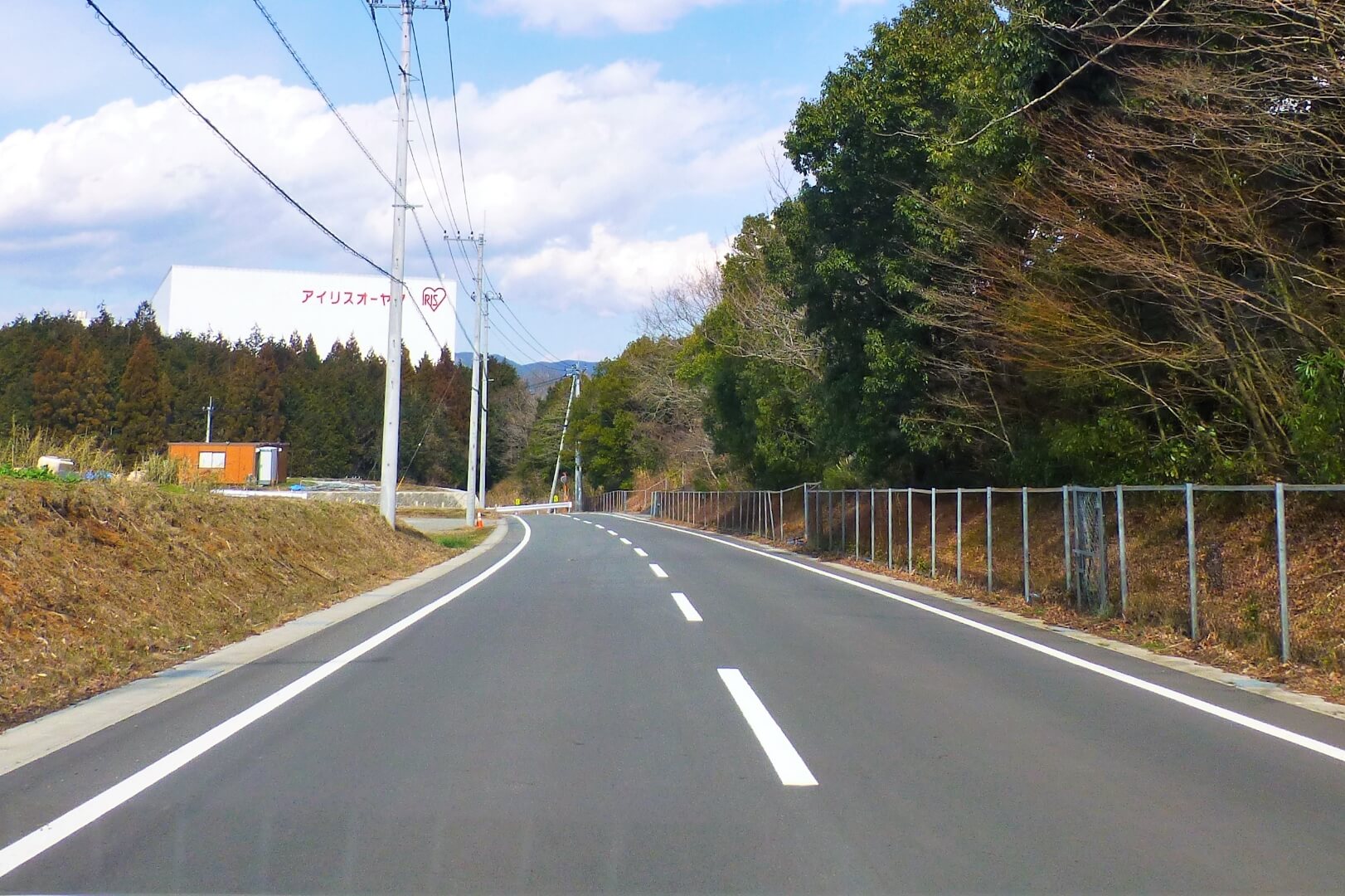 正面の森の奥にアイリスオーヤマの白い工場が見えてくる